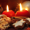 Zwei brennende rote Kerzen zwischen Plätzchen und Weihnachtsdeko