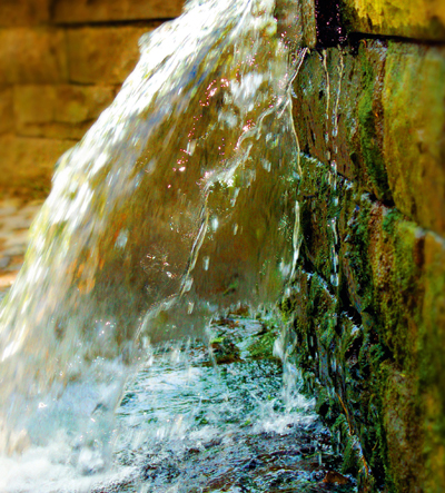 Ein Wasserstrahl stürzt in ein Steinbecken